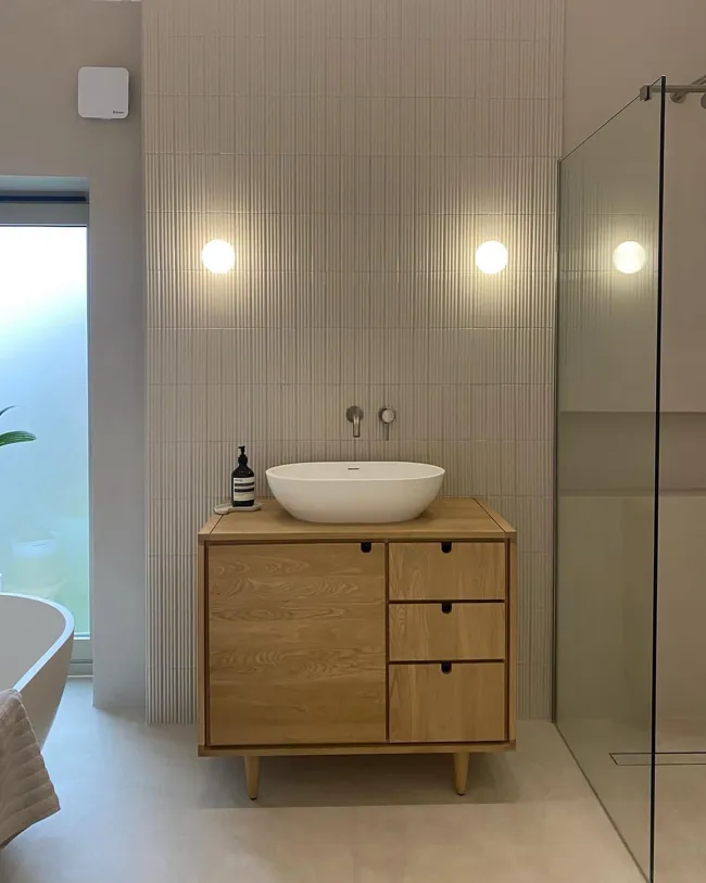 Ahşap lavabo dolabı arkasında açık tonlu microcement duvar