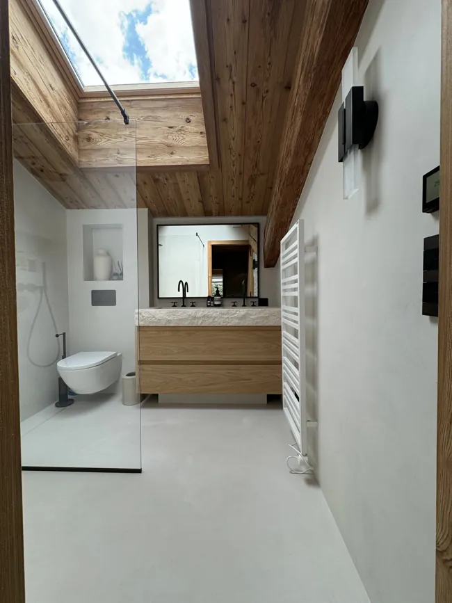 Ahşap tavanlı banyoda açık tonlu microcement yüzeyler