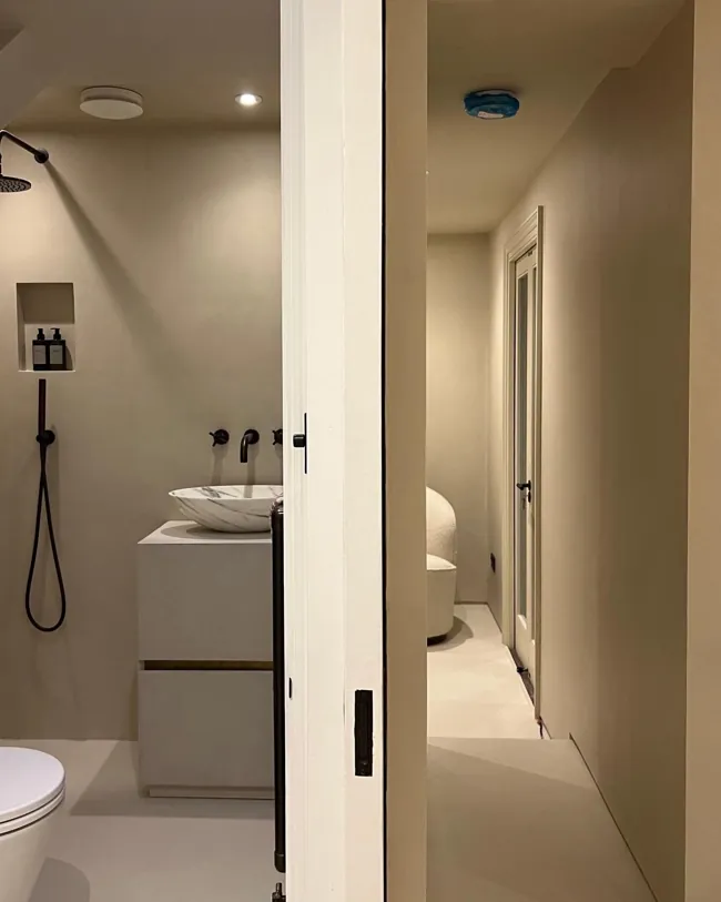 Lavabo ve duş alanına açılan geçişte açık tonlu microcement yüzeyler