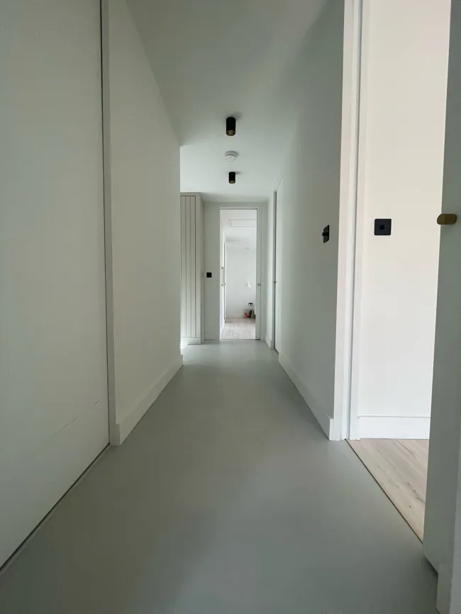 Dar koridorda açık tonlu microcement duvar ve zemin yüzeyleri