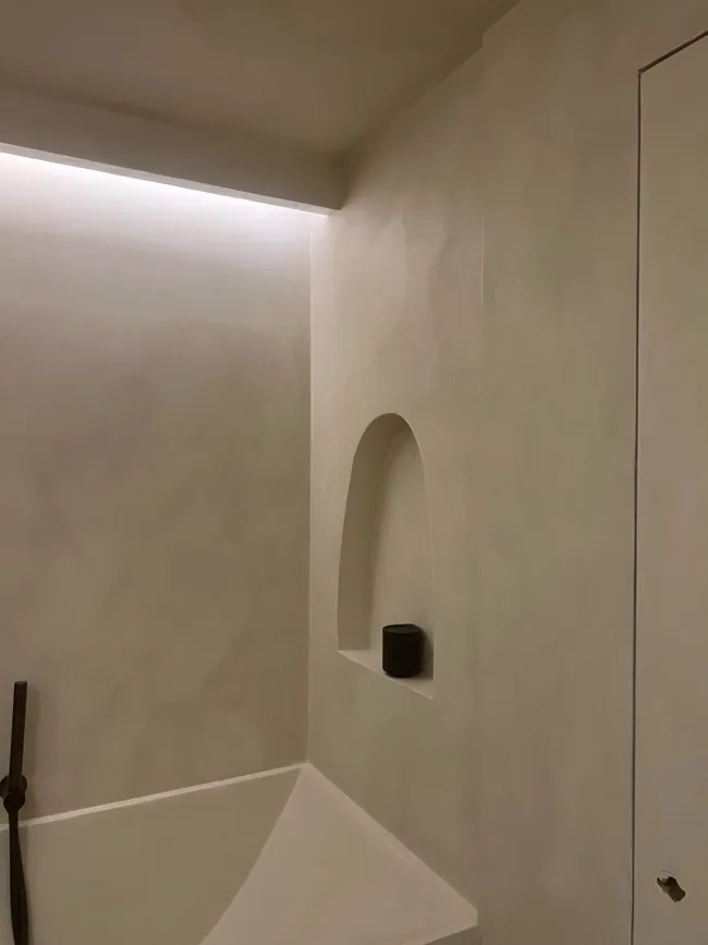 Duş alanında gömme niş ve açık tonlu microcement duvar yüzeyi