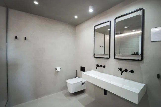 Çift lavabo ve dikdörtgen aynalar arkasında gri microcement duvar
