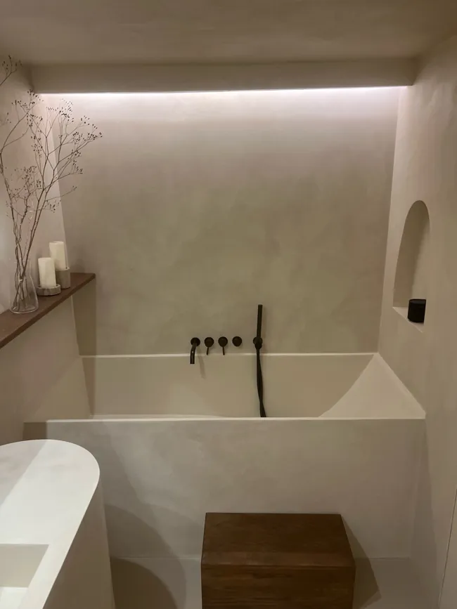 Küvet ve gömme niş çevresinde açık tonlu microcement duvar