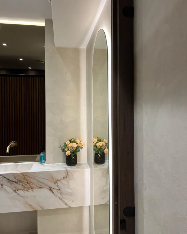 Dikdörtgen ayna ve lavabo çevresinde açık tonlu microcement duvar